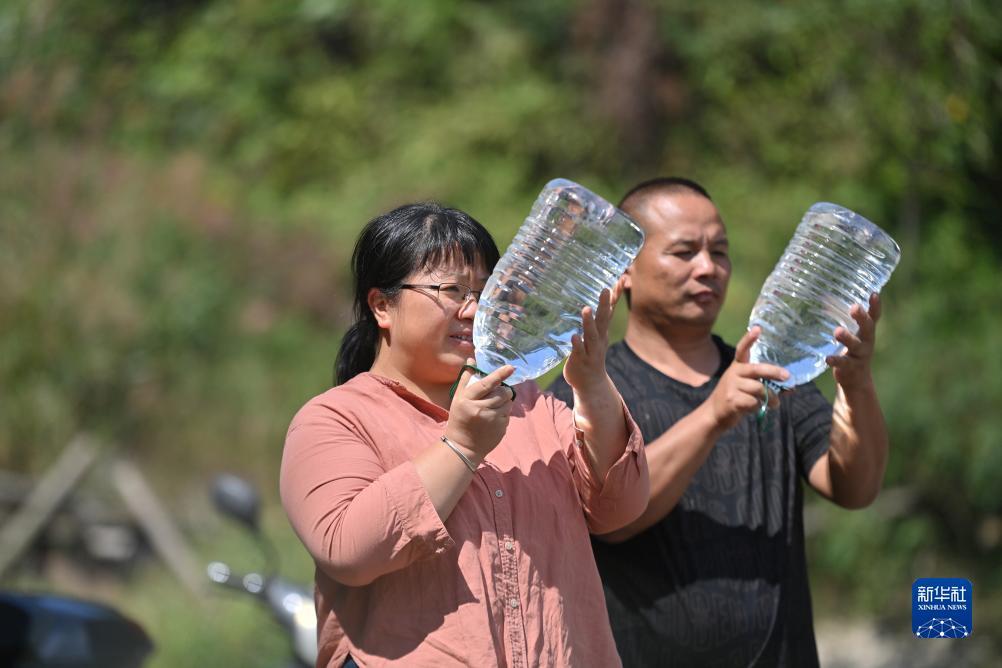 楊寧（左）在查看村民剛剛采集的水樣，為山泉水引水工程做準備（10月8日攝）。新華社記者 黃孝邦 攝